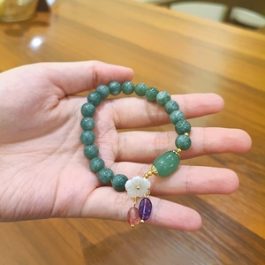Pulsera de cuentas de piedra verde con dije de flor de concha blanca y toques de color