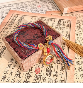 Detail of handmade ethnic braided bracelet with golden sutra box and colorful tassels