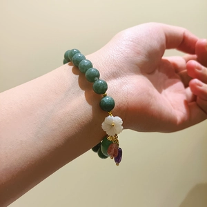 Pulsera artesanal con piedras verdes y un elegante colgante de flor blanca para mujer