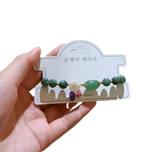 Elegante pulsera de cuentas con piedras verdes y dijes de flores en cartulina