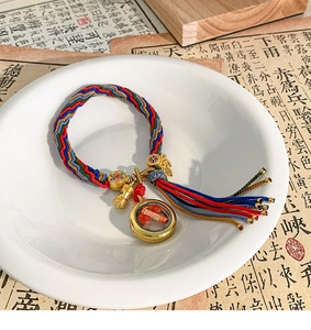 Detailed close-up of woven Tibetan bracelet with a golden Gau box and colorful tassels