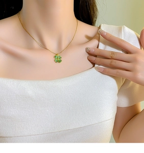 Dettaglio della collana con quadrifoglio dorato e opale verde indossata su una maglia bianca