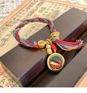 Detailed close-up of colorful woven ethnic bracelet with golden prayer pendant on wood