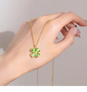 Dettaglio della collana a quadrifoglio dorata con opale verde tenuta per mostrare la misura