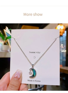 Gros plan d'un collier lune en argent avec incrustation d'ormeau et pendentif étoile