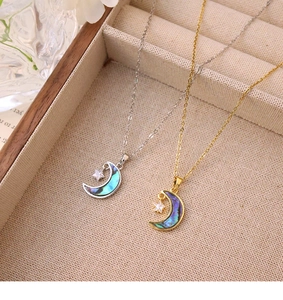 Détail de pendentifs lune et étoile en or et argent avec nacre sur plateau à bijoux