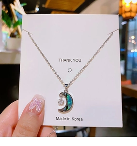 Détail d'un collier avec pendentif en forme de lune et incrustation d'abalone irisée