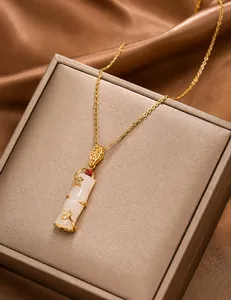Detail of bamboo pendant necklace with white jade imitation and ruby accent in 18k gold finish