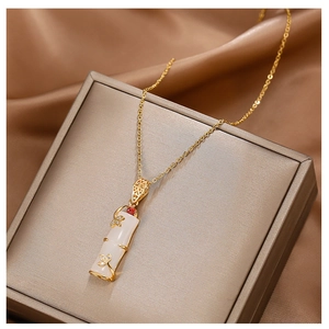 Detailed macro view of a 18k gold bamboo pendant with white jade texture on silk