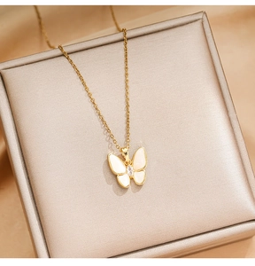 Detailed close-up of a golden butterfly pendant with shell inlay and zircon on a jewelry box