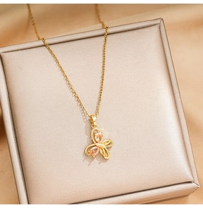 Detailed close-up of a golden butterfly necklace with a zircon drop on a jewelry box