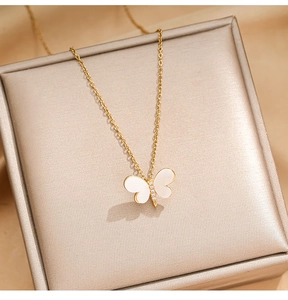 Detail of butterfly necklace with white shell inlay and zircons on gold silk background