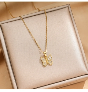 Close-up of gold butterfly necklace with pavé zircon wings on champagne satin gift box