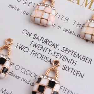Macro shot of pink and black checkered alloy bag charms with sparkling rhinestone handles