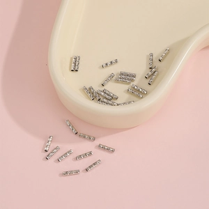 Dettaglio di distanziatori cilindrici in argento con trama a taglio diamantato per gioielli DIY