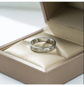 Macro shot of silver titanium steel ring with roman numerals and diamond in a gift box