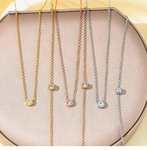 Detailed close-up of gold, rose gold and silver necklaces with a single round zircon