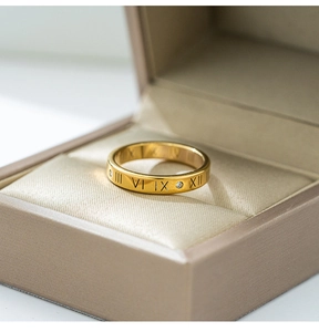 Detailed macro view of gold-plated roman numeral ring with zircon in a premium gift box