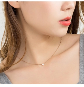 Close-up of a rose gold titanium necklace with a single diamond pendant on a female model