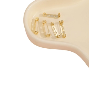Cinque basi per spille fai-da-te placcate in oro a 3 fori su un vassoio di ceramica