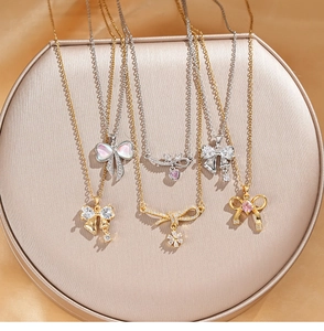 Detail of five bow pendant necklaces with colorful zircon stones and tassels on a gold stand