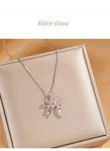 Detail of silver bow necklace with pink gemstone pendant on champagne jewelry box
