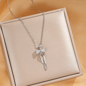 Macro shot of silver bow pendant with cubic zirconia on luxury silk background
