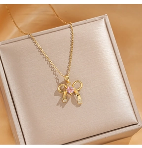 Detail of gold bow necklace featuring a pink zircon pendant and sparkling micro-crystals