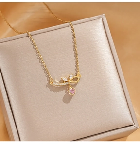Close-up of golden bow necklace with pink heart pendant and zircon in a jewelry box