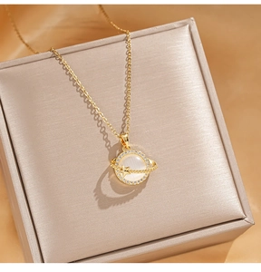 Close-up of golden planet pendant with opal stone and zircon star ring on silk background