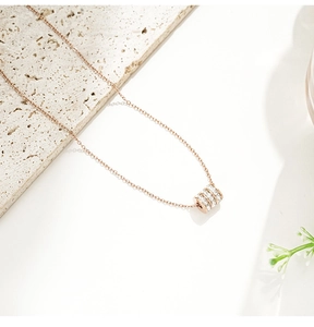 Detailaufnahme des roségoldenen Zylinderanhängers mit drei Reihen Kristallen an der Kette