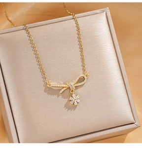 Detailed macro view of golden bow pendant with zircon and flower charm on jewelry box