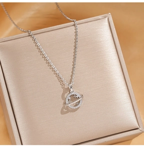 Macro shot of silver-tone Saturn pendant with shimmering pavé stones on champagne satin