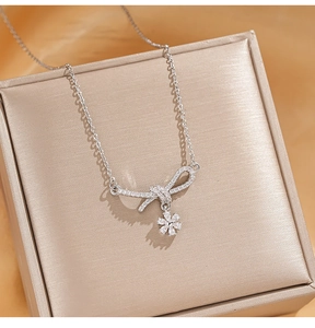Detailed view of shimmering zircon bow necklace with flower pendant in a gift box