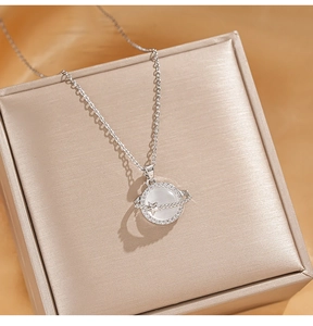 Macro detail of cat's eye stone planet pendant necklace in a silk jewelry box