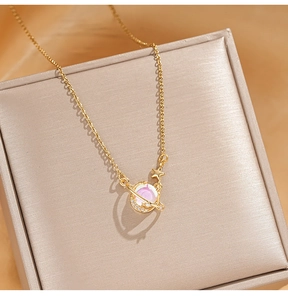 Detailed close-up of golden planet pendant with opal sphere and star on stainless chain