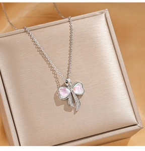 Macro shot of zircon bow pendant with pink shell inlay on titanium steel chain