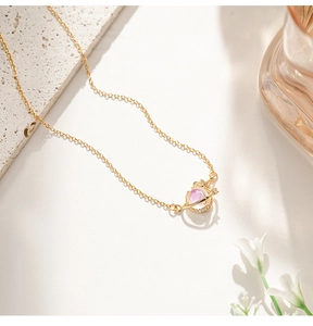 Detail of gold planet pendant with opal stone, cubic zirconia and star charm on chain