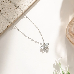 Detail of bow-shaped titanium steel necklace featuring shimmering zircon and pearls