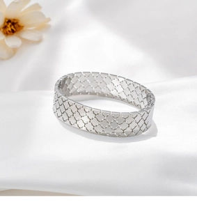 Dettaglio del bracciale largo in acciaio inossidabile argento lucido con quadrifogli
