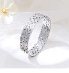 Dettaglio macro del bracciale rigido largo argento con classica trama trapuntata