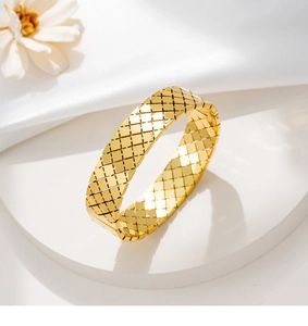 Dettaglio macro di un bracciale in acciaio inossidabile dorato con trama trapuntata classica