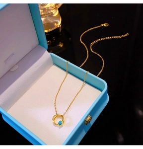 Detaillierte Makroansicht der Goldkette mit blauem Steinanhänger in hellblauer Schmuckschatulle