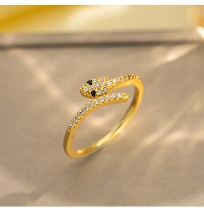 Close-up of gold snake open ring featuring white crystals and black gem eyes detail
