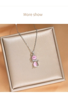 Détail du collier pendentif chat rose en œil de chat posé sur un écrin à bijoux doré