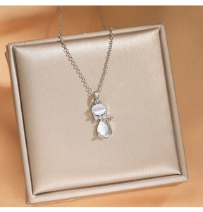 Gros plan du collier pendentif chat en œil de chat rose sur une boîte à bijoux en soie dorée