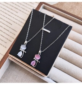 Détail du collier pendentif chat en opale rose sur fond de livre vintage chic