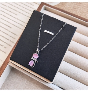 Détail du pendentif chat rose en pierre avec nœud argenté sur une carte cadeau