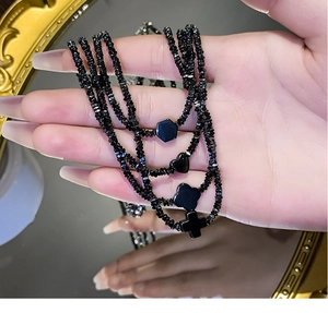 Detail van zwarte titanium kralenketting met hart- en kruisbedels in de hand