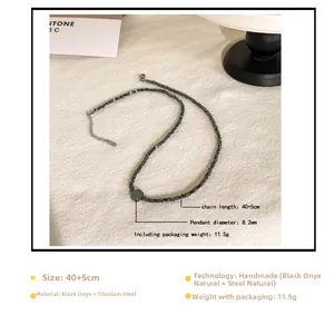 Detail van hematiet kralenketting met titaniumstalen hanger op stoffen ondergrond